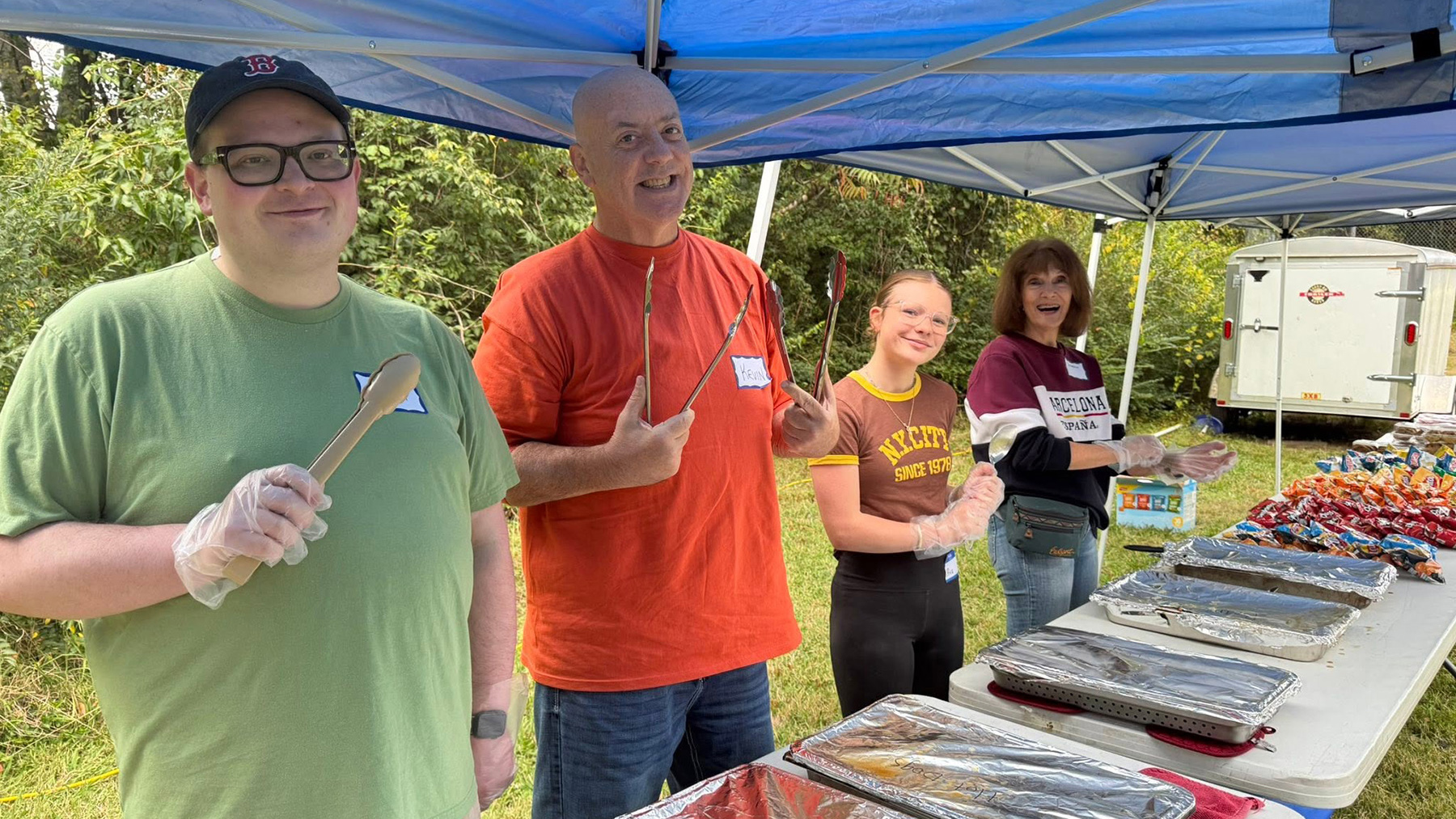 Four smiling Christ UMC members stand ready to serve dinner during our annual Holy Smoke BBQ in Franklin, TN.