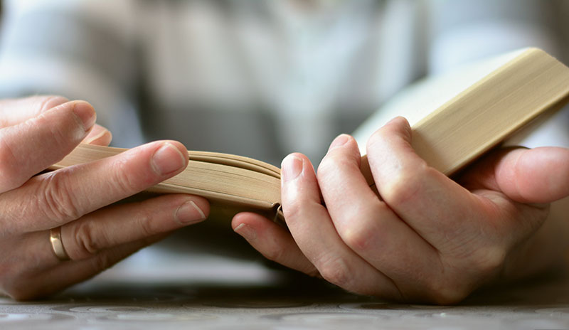 Close-up of hands holding an open book.