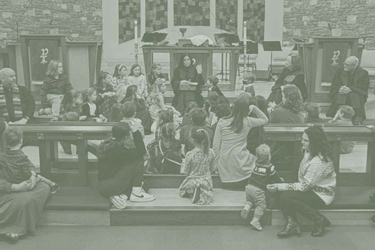 Large group of children sits in front of the altar and listens as a woman gives the children's sermon at Christ UMC..