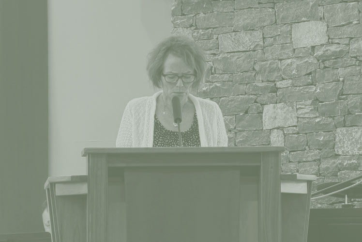 Close-up of a Scripture reader reading from the Bible at the lectern during Sunday morning worship.
